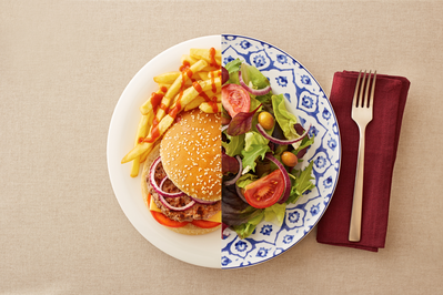 plate showing balanced diet with half salad half burger and fries